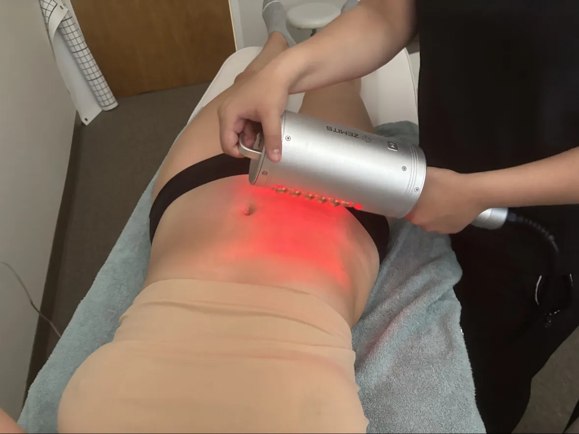 A provider applying an Endo roller massage handpiece to a guest’s abdomen