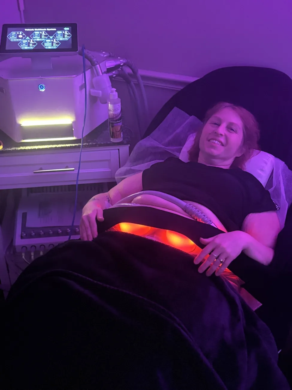 A guest reclining in The Lipo Lounge under pink lighting in Jacksonville