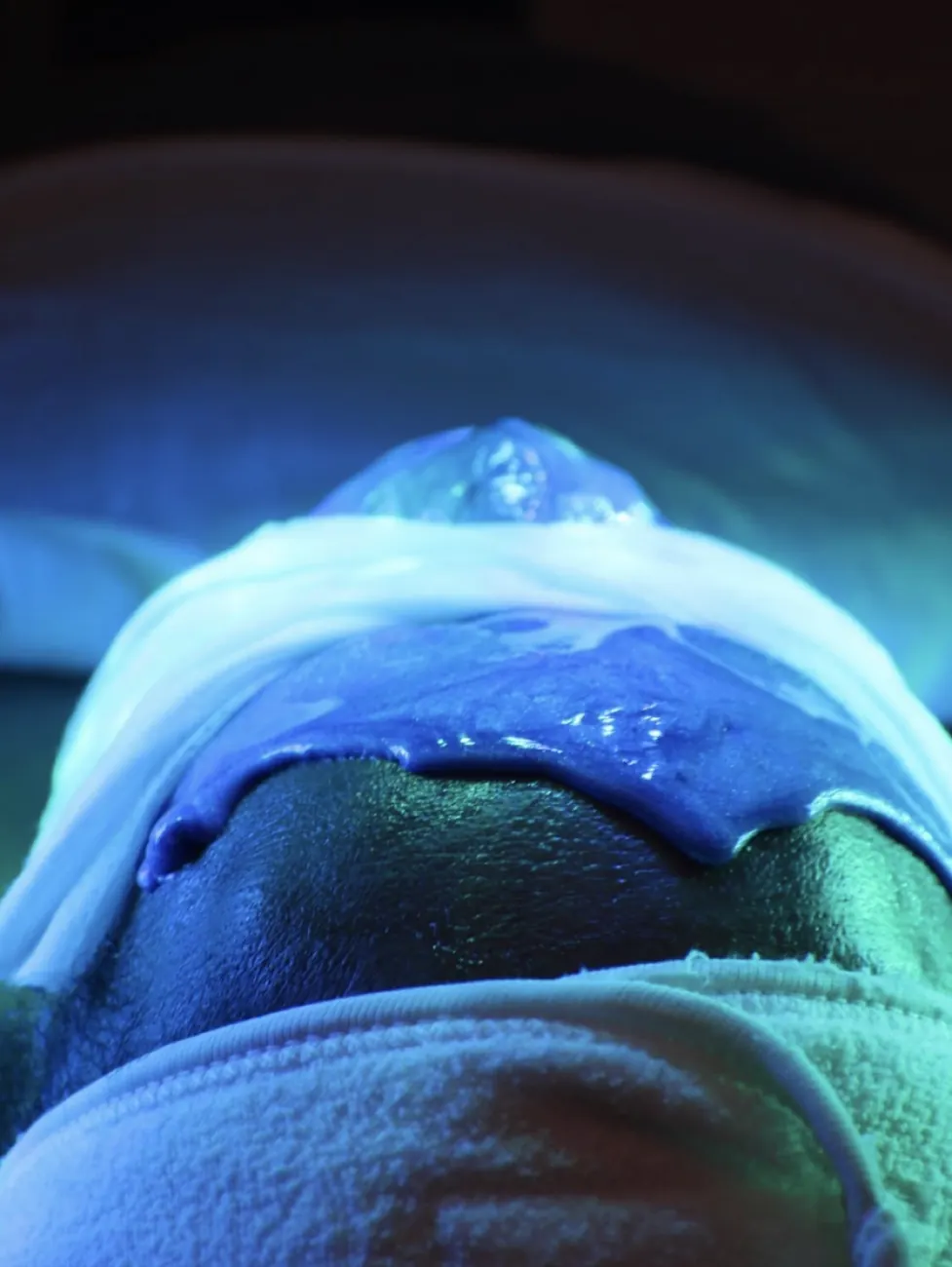 A guest wearing eye protection beneath blue facial-treatment light